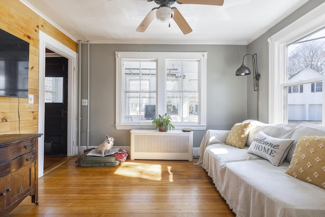 sitting room featuring a healthy amount of sunlight, radiator heating unit, ornamental molding, and hardwood / wood-style flooring