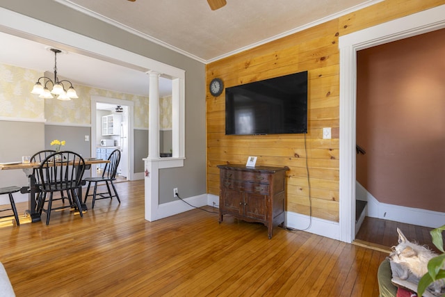 living area with crown molding, ceiling fan, baseboards, hardwood / wood-style flooring, and ornate columns