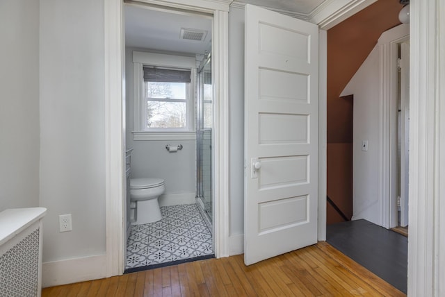 full bathroom featuring radiator, visible vents, hardwood / wood-style flooring, a shower stall, and toilet