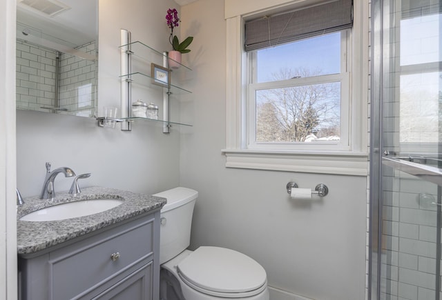 bathroom with visible vents, toilet, vanity, and tiled shower