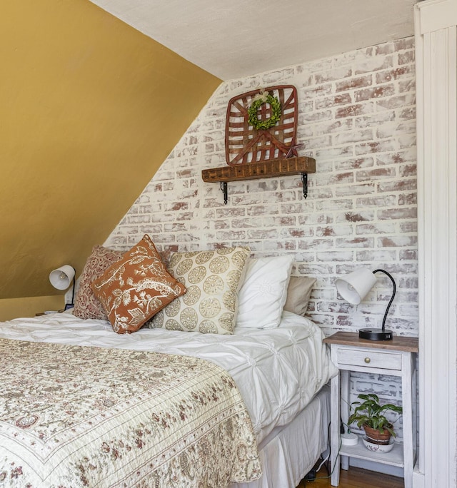 bedroom featuring vaulted ceiling and brick wall