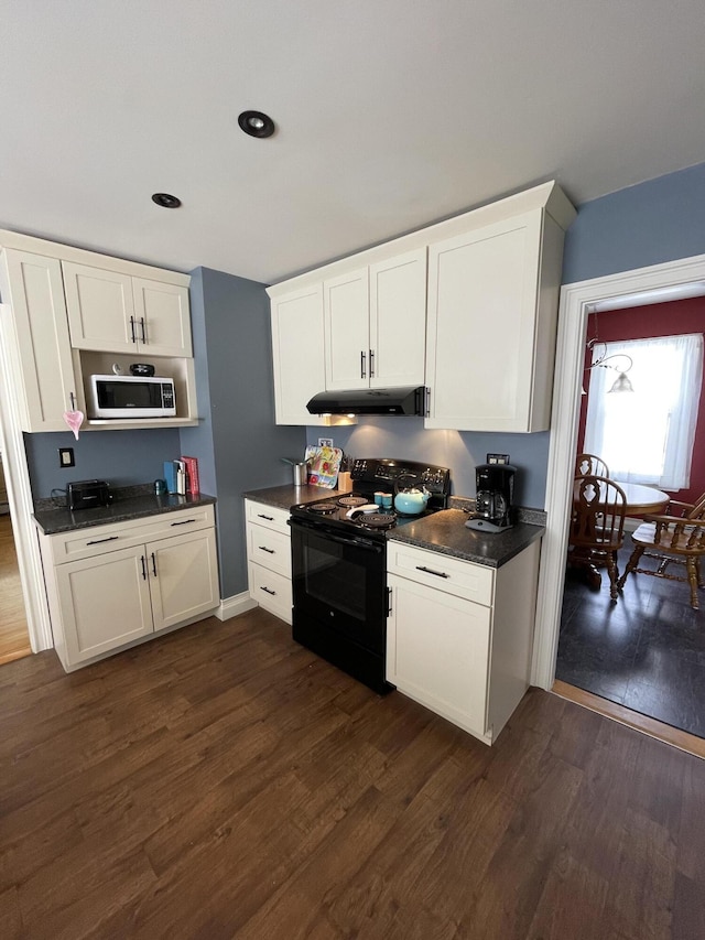 kitchen with dark wood-style floors, dark countertops, electric range, white microwave, and under cabinet range hood