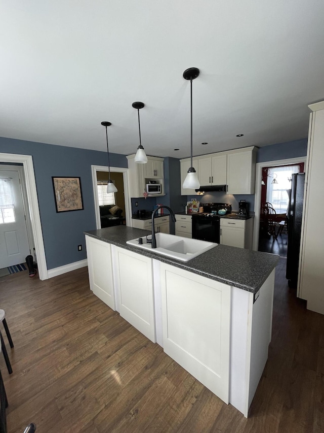 kitchen featuring dark wood finished floors, dark countertops, white cabinets, a sink, and black appliances