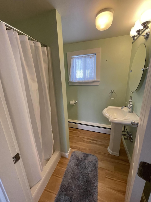 full bath featuring a baseboard heating unit, baseboards, wood finished floors, and a shower with curtain