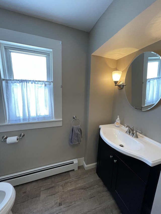 bathroom featuring baseboards, toilet, wood finished floors, baseboard heating, and vanity