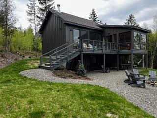 back of property featuring stairway, a lawn, a deck, a sunroom, and a patio