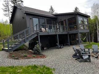 back of property featuring stairs, a deck, and a sunroom