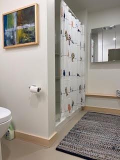 bathroom featuring a shower with shower curtain, baseboards, and toilet