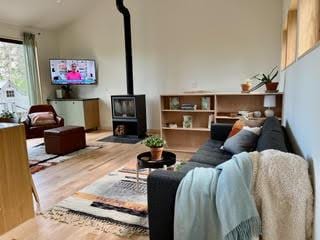 living area featuring a wood stove, lofted ceiling, and wood finished floors