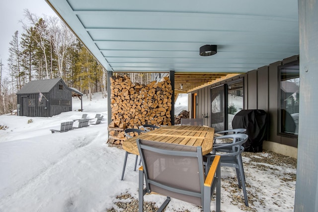 snow covered patio with a storage shed, an outdoor structure, and area for grilling