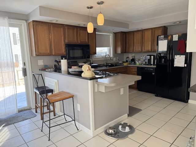 kitchen with a peninsula, black appliances, light tile patterned floors, and a sink