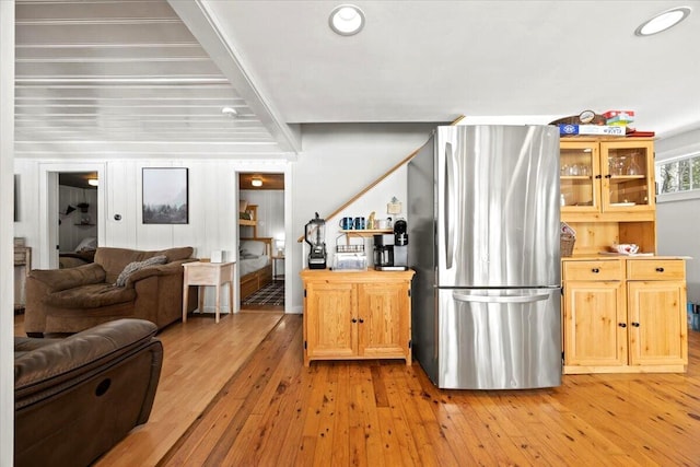 kitchen with light wood-type flooring, open floor plan, freestanding refrigerator, recessed lighting, and glass insert cabinets