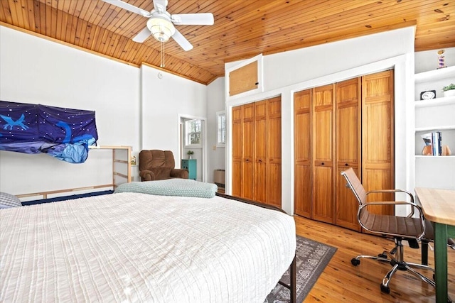 bedroom featuring multiple closets, ceiling fan, wood ceiling, light wood-type flooring, and lofted ceiling