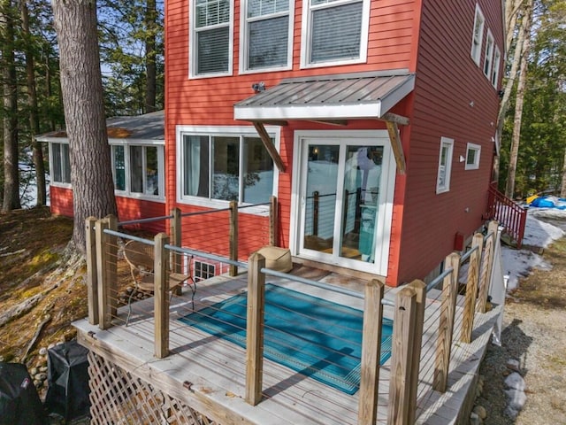 rear view of property featuring metal roof, a wooden deck, and a standing seam roof