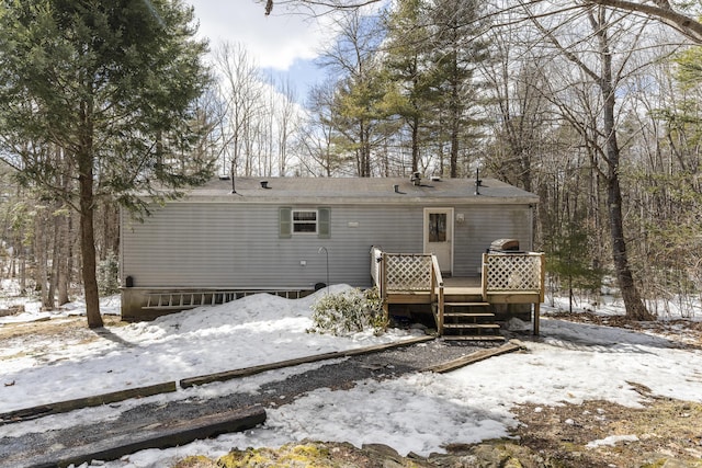 snow covered rear of property with a deck