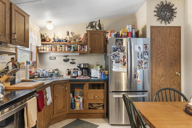 kitchen featuring open shelves, stainless steel appliances, a textured ceiling, dark countertops, and brown cabinets