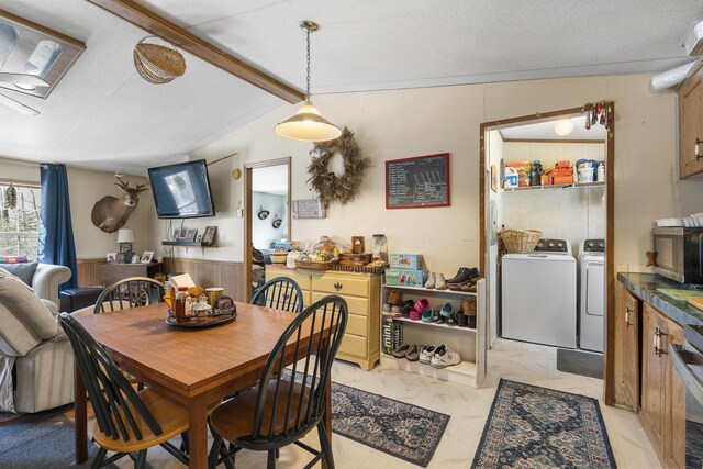 dining area with vaulted ceiling with beams, a wainscoted wall, wood walls, a textured ceiling, and separate washer and dryer