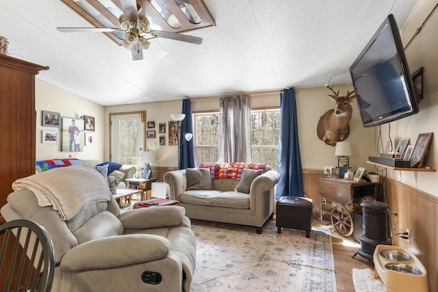 living room with a wainscoted wall, lofted ceiling, a textured ceiling, and wood finished floors