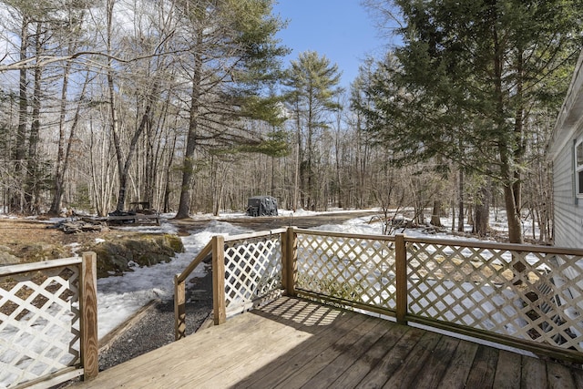 snow covered deck with a forest view