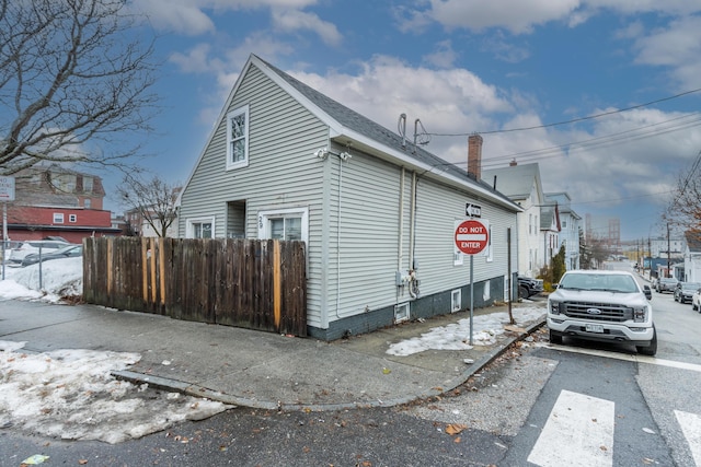 view of property exterior featuring a chimney and fence