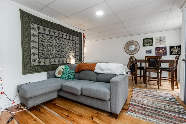 living room with a drop ceiling and wood finished floors