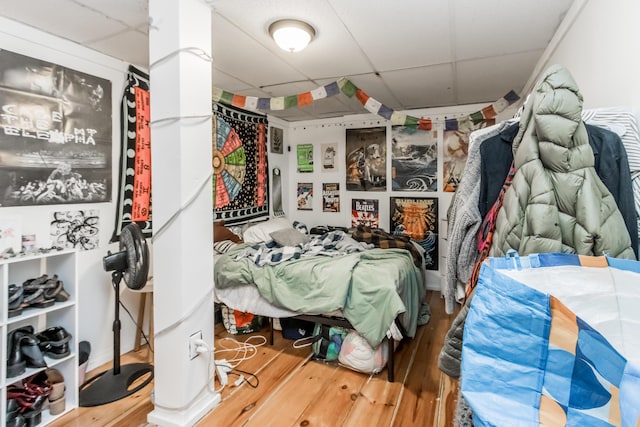 bedroom featuring a drop ceiling and wood finished floors