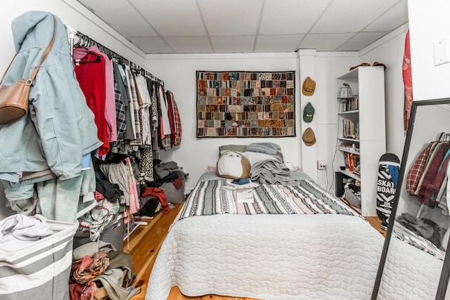 bedroom featuring a drop ceiling and wood finished floors