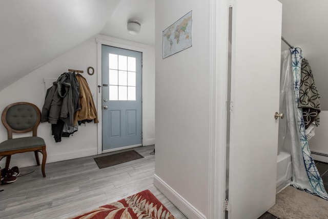 interior space featuring light wood-type flooring, baseboards, and lofted ceiling