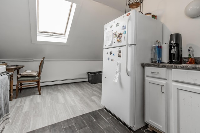 kitchen with a skylight, freestanding refrigerator, white cabinets, and wood finish floors