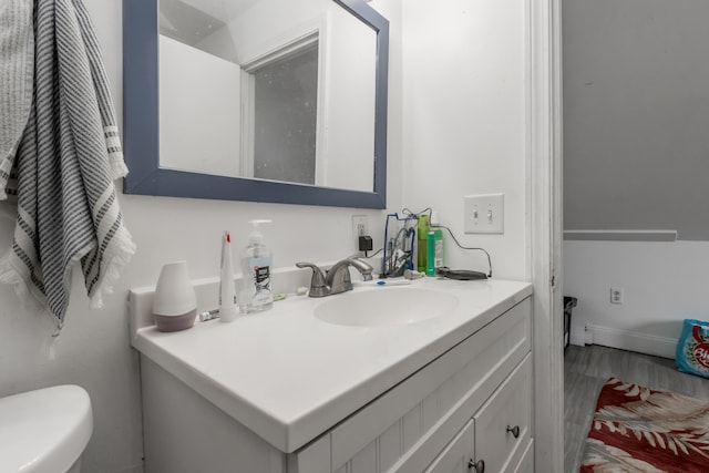 bathroom featuring toilet, wood finished floors, and vanity