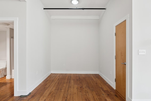 spare room featuring wood-type flooring and baseboards