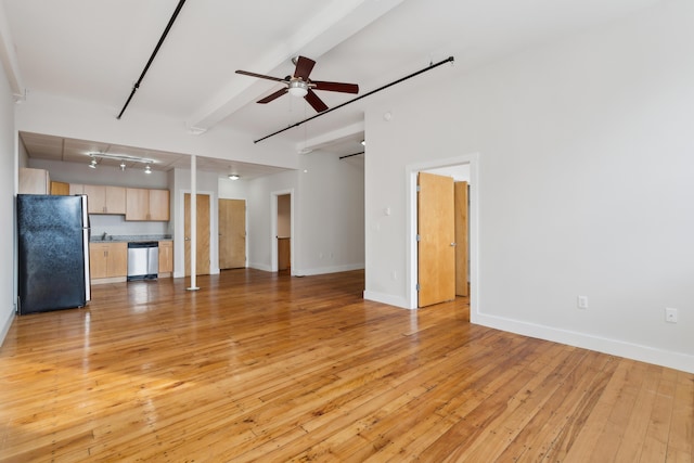 unfurnished living room featuring light wood-style flooring, ceiling fan, track lighting, beamed ceiling, and baseboards