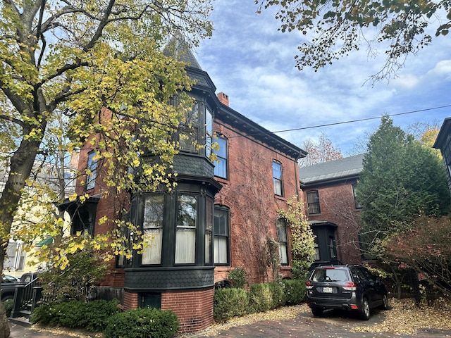 view of property exterior with a chimney and brick siding
