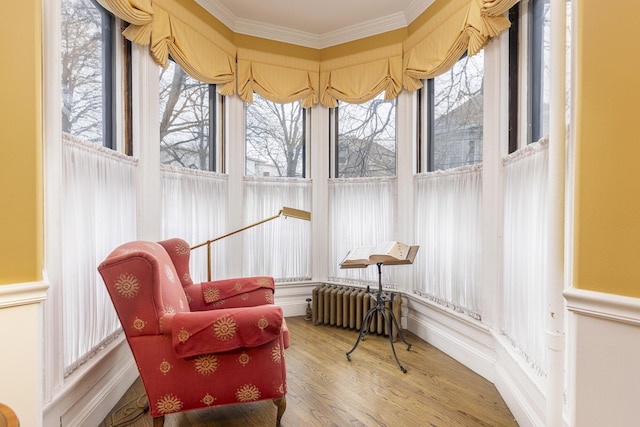 sunroom with radiator heating unit, ornamental molding, and wood finished floors