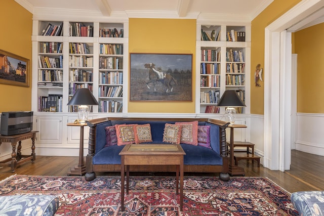 living area featuring a wainscoted wall, wood finished floors, ornamental molding, and built in shelves