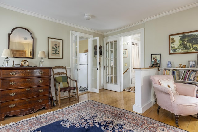 living area featuring hardwood / wood-style flooring, ornamental molding, and french doors