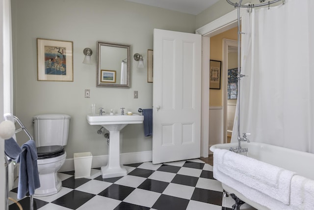 bathroom with tile patterned floors, toilet, baseboards, and a tub to relax in