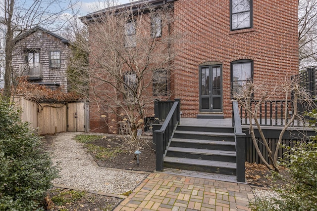 back of house featuring brick siding and french doors