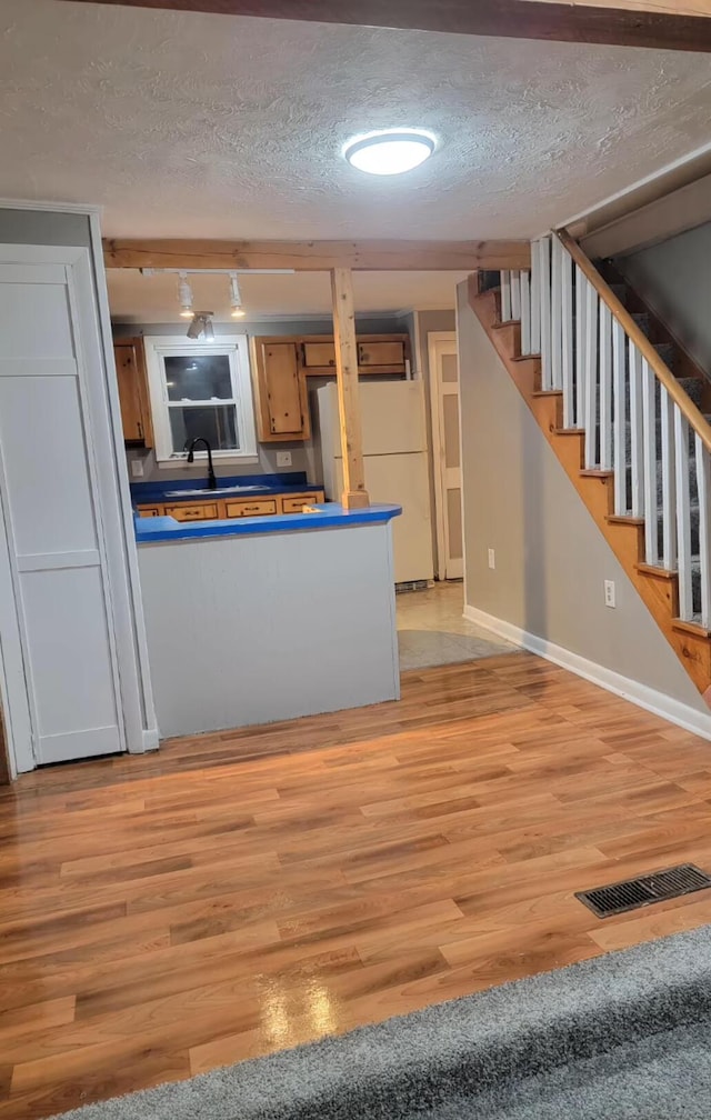 32 Maple St, Fairfield, ME 04937 - kitchen with a textured ceiling, light wood-style flooring, dark countertops, baseboards, and freestanding refrigerator