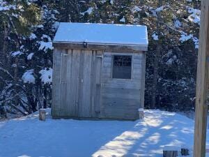 snow covered structure featuring an outbuilding