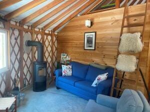 living area with vaulted ceiling with beams, a wood stove, and wooden walls