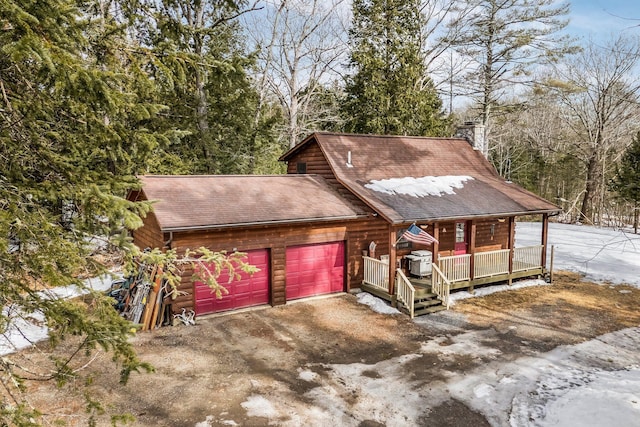 view of front facade with driveway, a tile roof, covered porch, a shingled roof, and a chimney