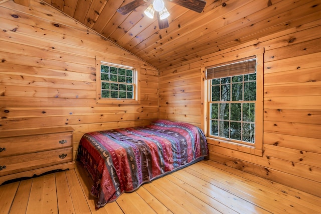 bedroom with lofted ceiling, ceiling fan, wood walls, wood-type flooring, and wooden ceiling