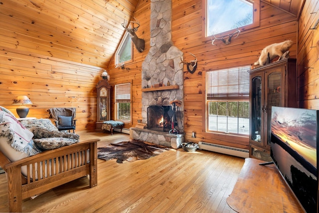 living area with hardwood / wood-style floors, high vaulted ceiling, a stone fireplace, wood walls, and a baseboard heating unit