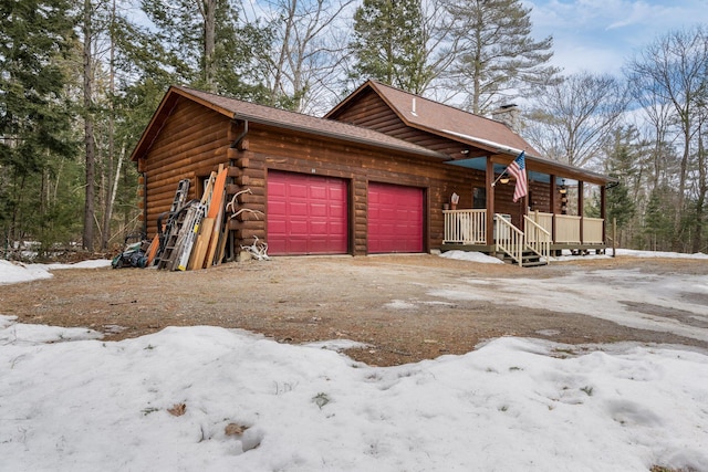 snow covered garage with a porch