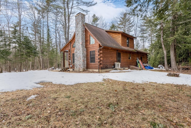 view of side of home featuring entry steps, cooling unit, a shingled roof, log exterior, and a chimney