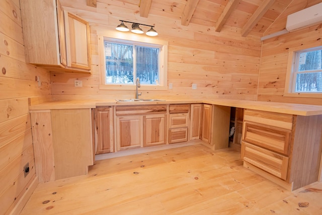 kitchen with light wood finished floors, wooden walls, an AC wall unit, light brown cabinetry, and a sink