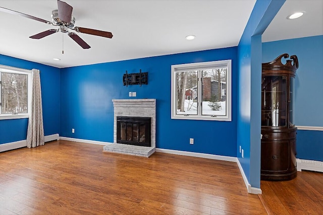 unfurnished living room with hardwood / wood-style floors, a fireplace, and baseboards