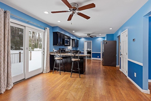 kitchen with dark wood finished floors, a breakfast bar, a peninsula, stainless steel appliances, and recessed lighting