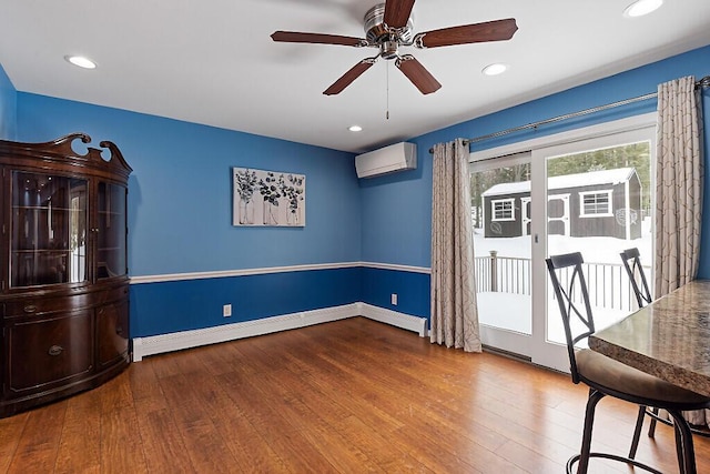 unfurnished dining area featuring hardwood / wood-style flooring, recessed lighting, a ceiling fan, baseboards, and a wall mounted air conditioner